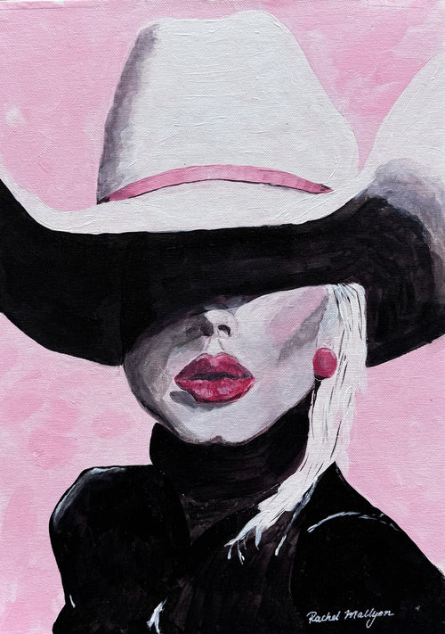 Western portrait with a sweeping white cowboy hat, black clothing and blush pink background.